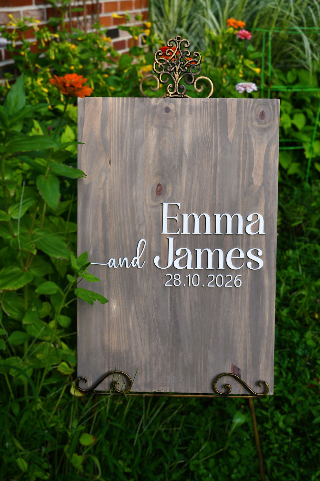 A rustic wooden wedding sign with the names 'Emma and James' and the date '28.10.